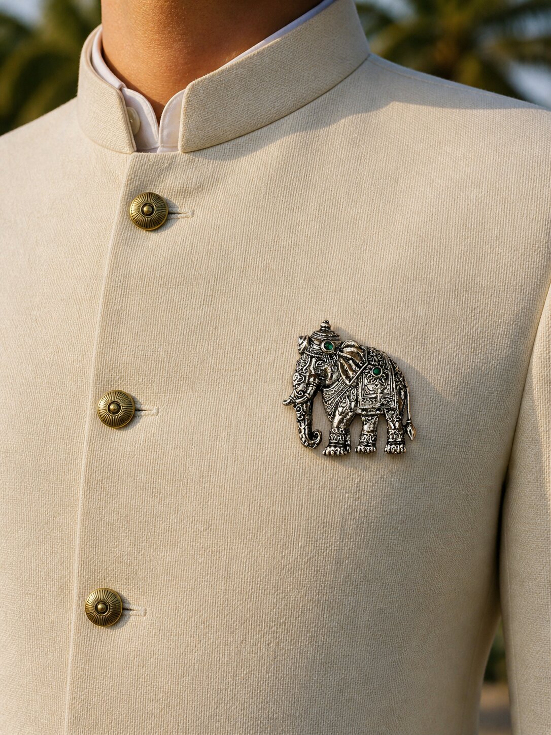 Silver-tone elephant brooch featuring intricate traditional detailing and green gemstone accents, perfect for weddings and festive wear.