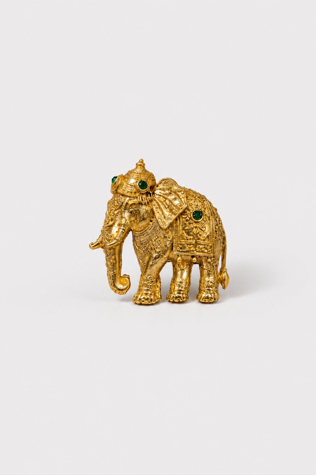 Gold-tone elephant brooch featuring intricate traditional detailing and green gemstone accents, ideal for wedding and festive wear.