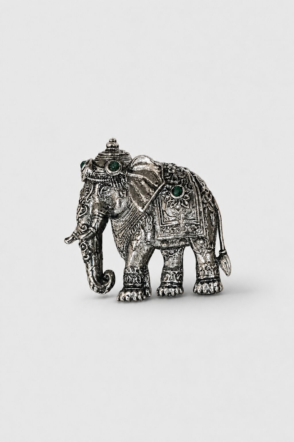 Silver-tone elephant brooch featuring intricate traditional detailing and green gemstone accents, perfect for weddings and festive wear.