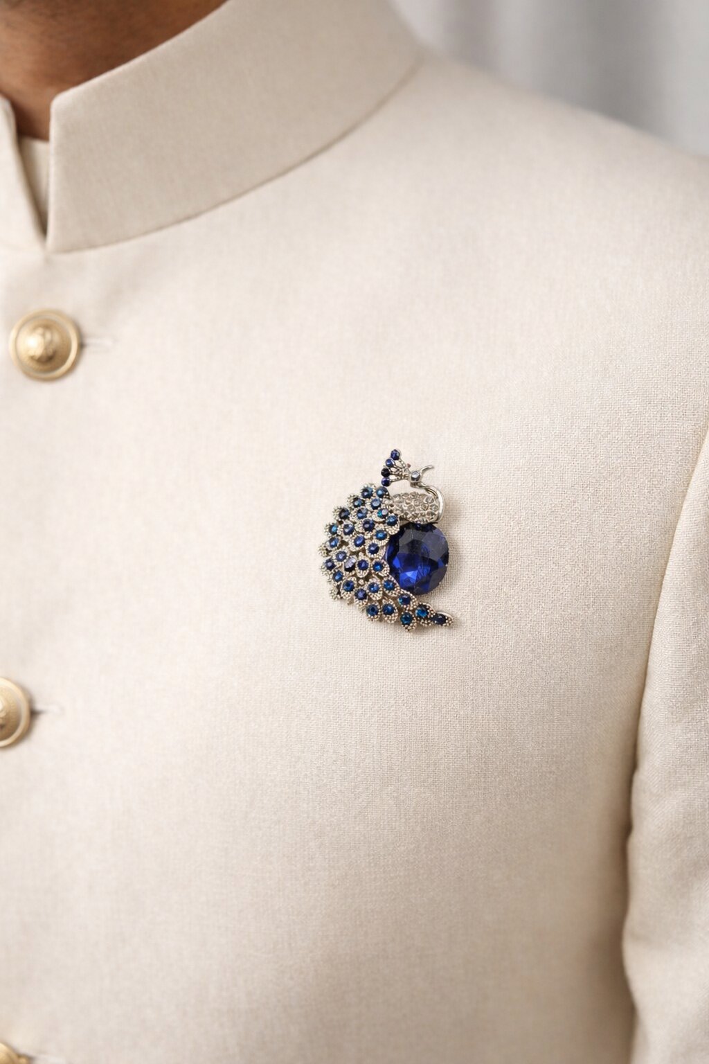 Silver-tone peacock brooch embellished with sapphire-blue crystals and a large deep blue gemstone centerpiece.