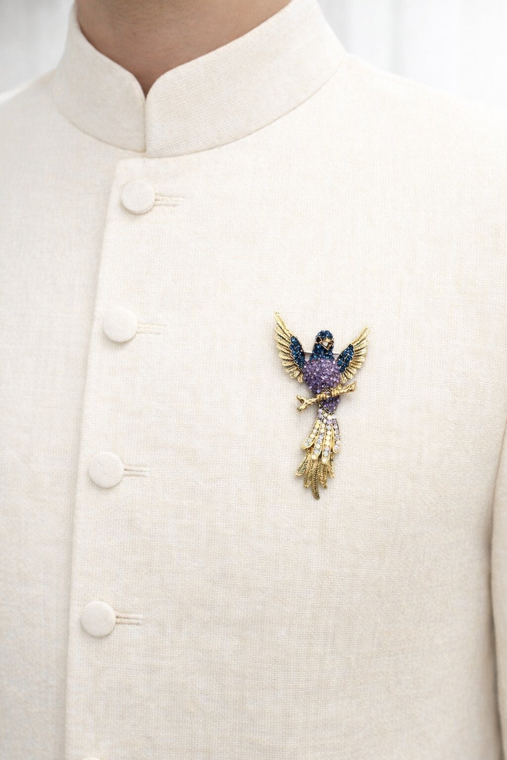 Gold-tone bird brooch adorned with blue and lavender crystals, featuring detailed wings and a sparkling crystal tail.