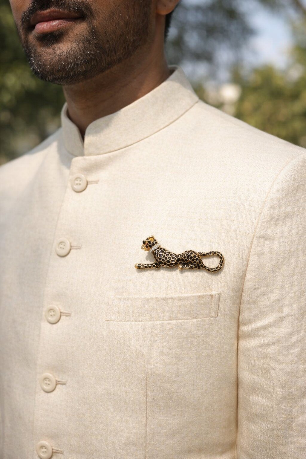 Gold-tone reclining leopard brooch with black enamel spots and crystal collar detail.