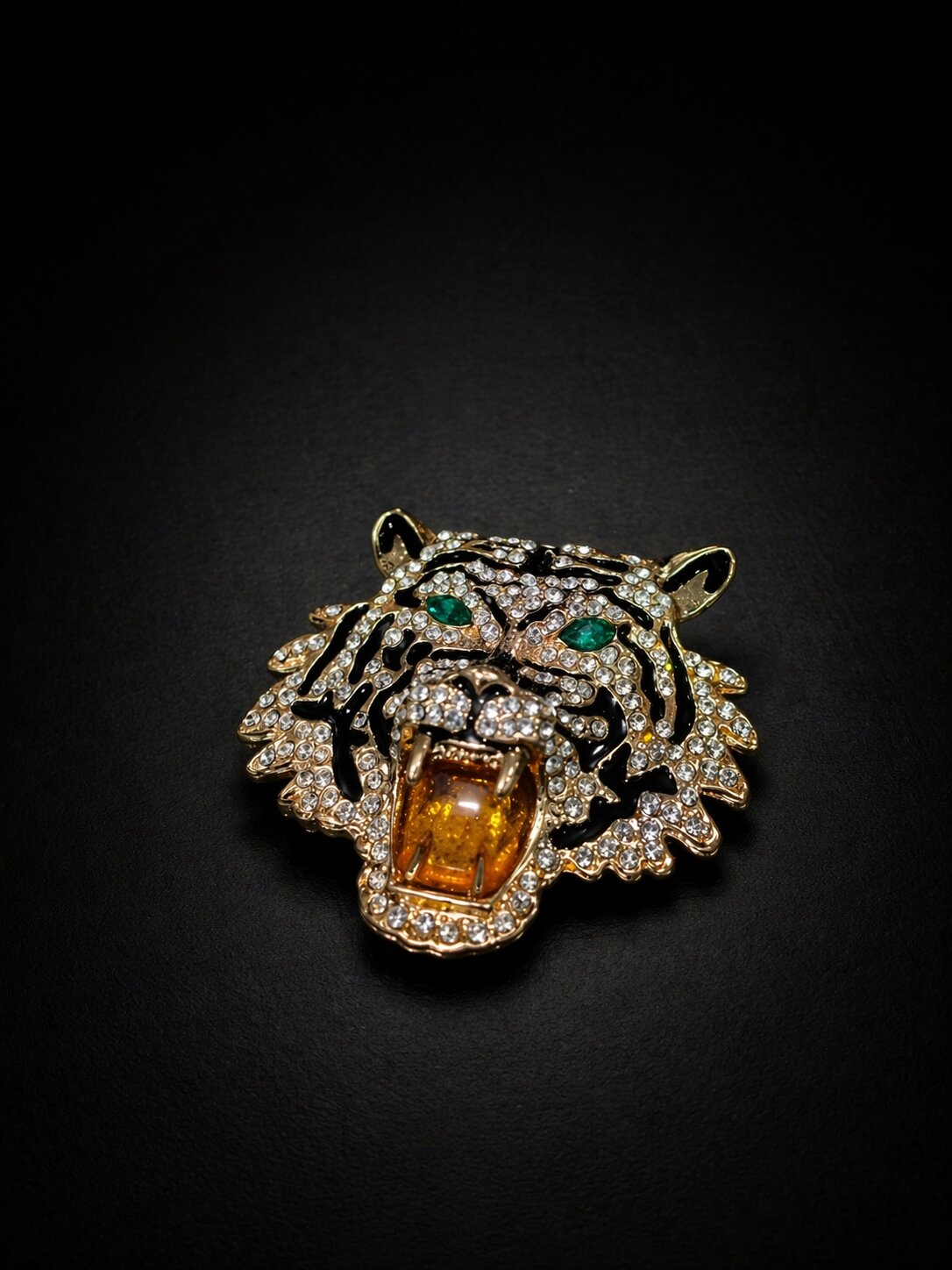 Gold-tone roaring tiger brooch with clear crystals, black enamel stripes, green eyes, and amber-colored mouth detail.