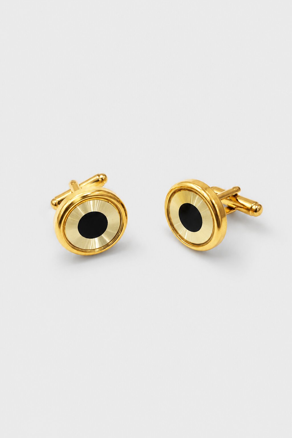 Round gold-tone cufflinks with black center detail and polished metallic finish.