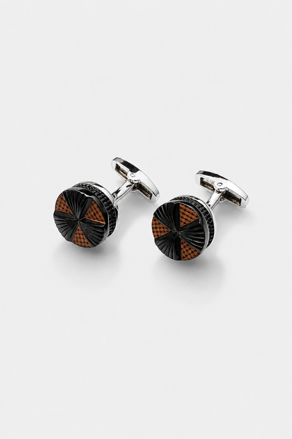 Round silver-tone cufflinks with black textured surface and bronze geometric accents for men's formal shirts.