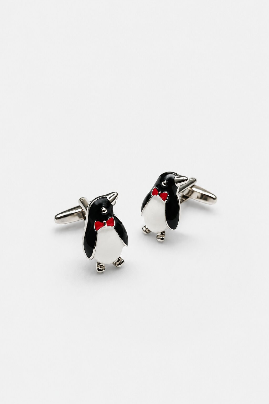 Penguin-shaped cufflinks with black and white enamel detailing and red accent bow tie design.