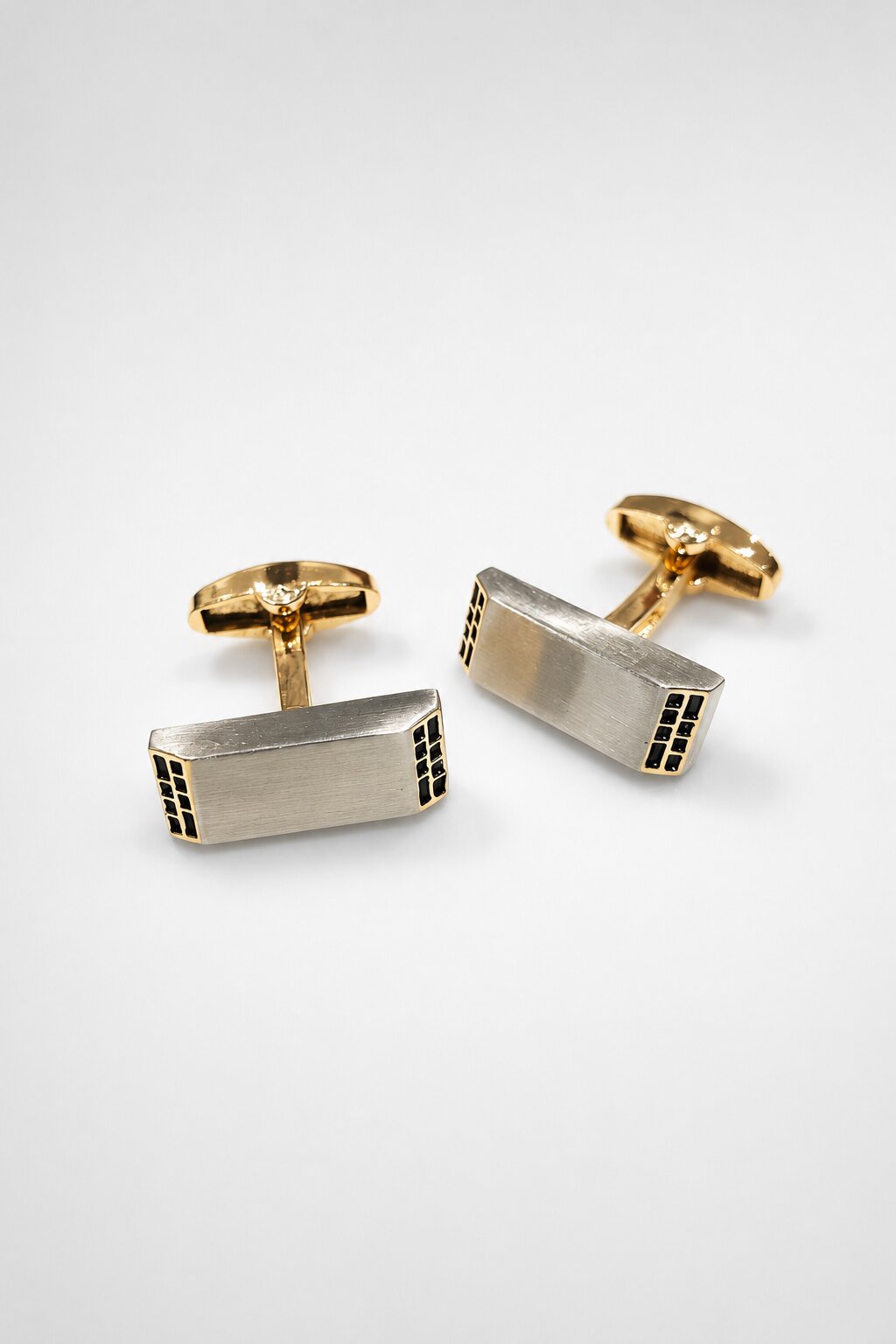 Two-tone rectangular cufflinks with brushed silver face, gold-tone hardware, and black accent detailing.