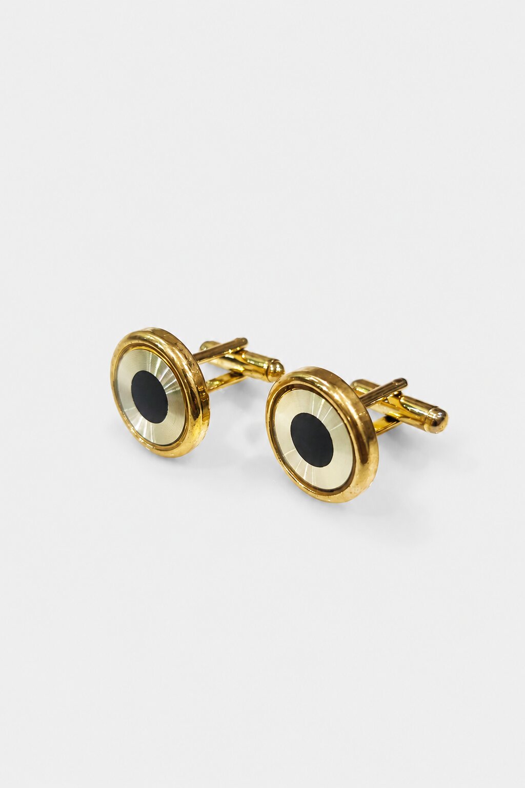 Round gold-tone cufflinks with black center detail and polished metallic finish.