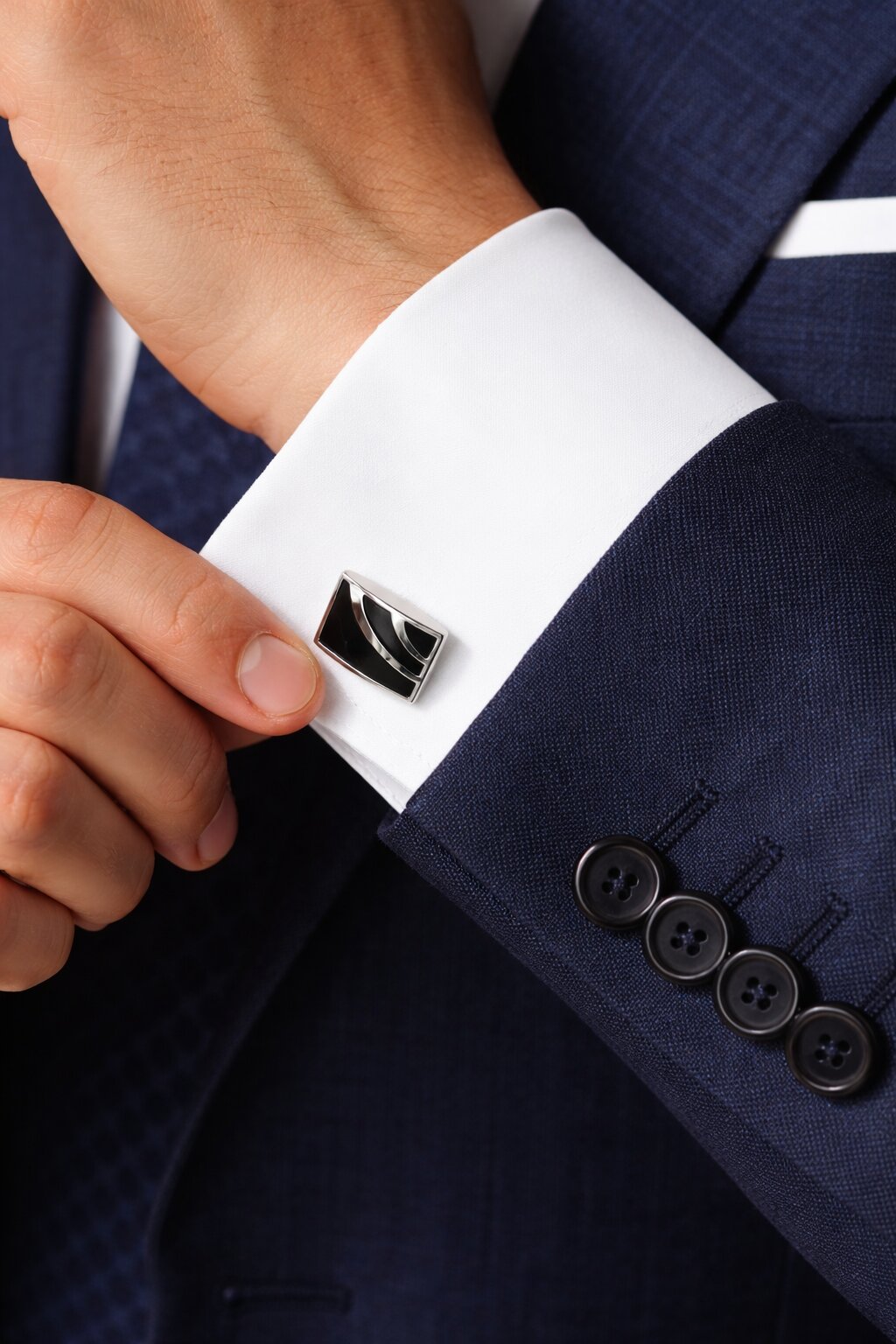 Black and silver rectangular cufflinks with curved geometric detailing and polished metal finish.
