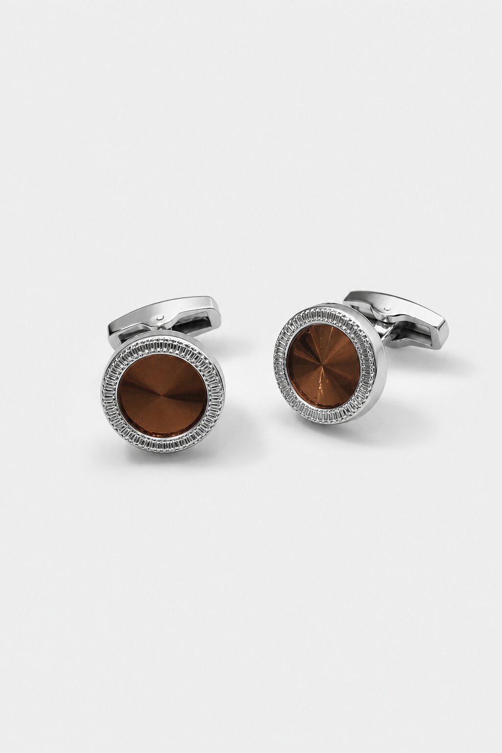 Round silver-tone cufflink with brushed copper center accent in a luxury formal setting.