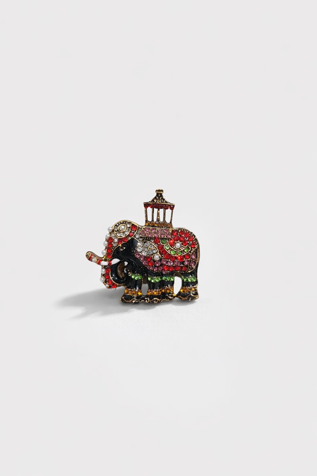 Multicolor crystal elephant brooch with pearl accents and decorative howdah in an antique gold-tone finish.