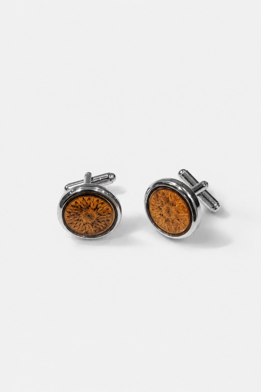 Round silver-tone cufflinks with amber floral pattern center and polished metal finish.