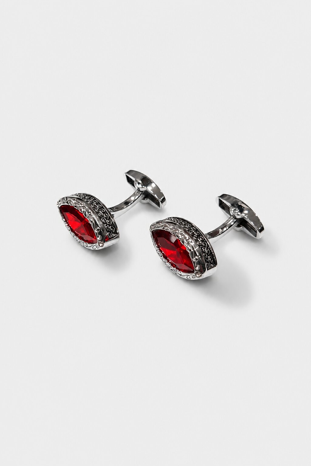 Silver cufflinks with red marquise-cut crystal centerpiece and ornate engraved border for men's formal shirts.