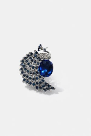 Silver-tone peacock brooch embellished with sapphire-blue crystals and a large deep blue gemstone centerpiece.