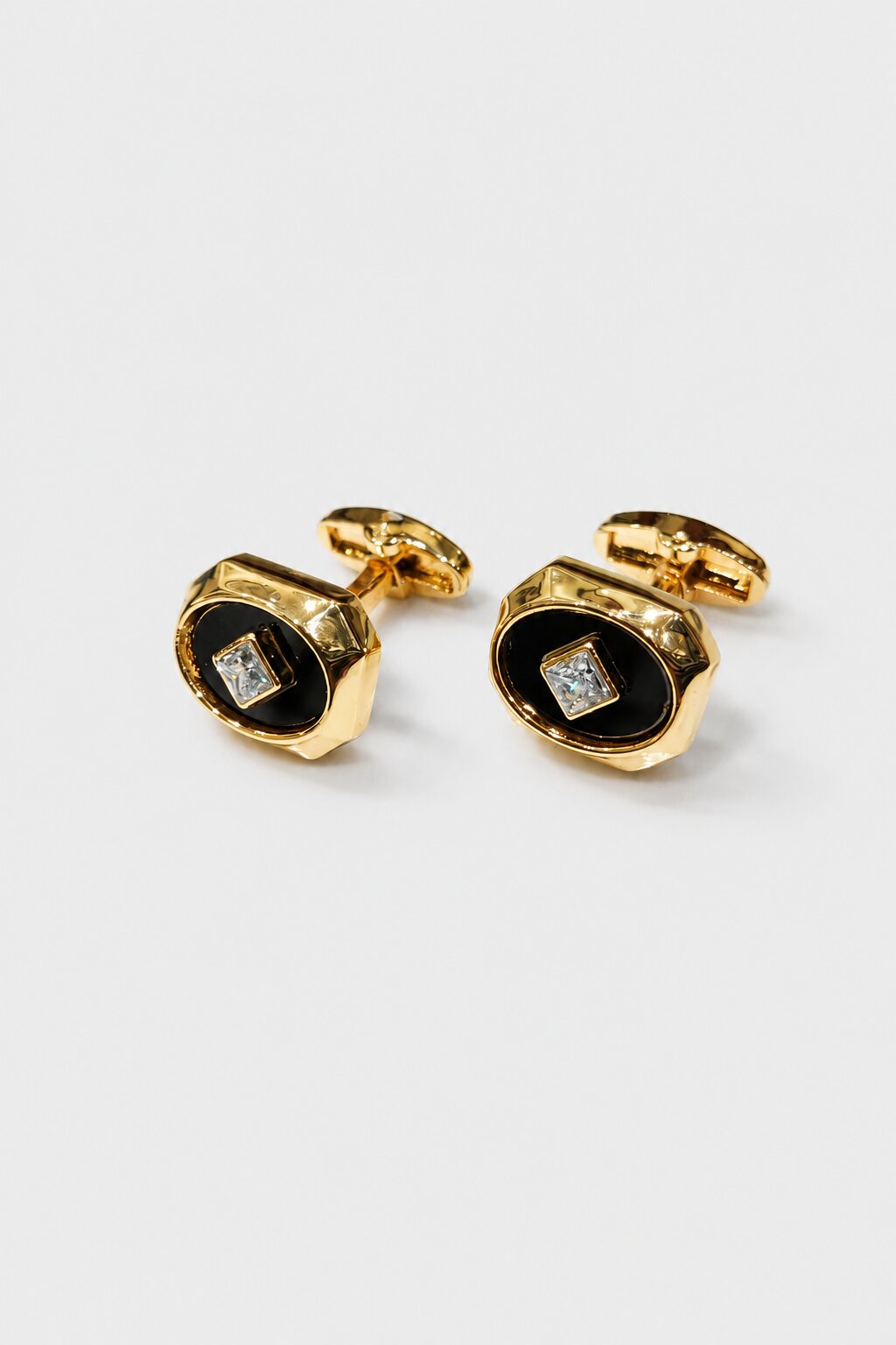 Gold octagonal cufflinks with black enamel center and square crystal accent in a polished luxury finish.