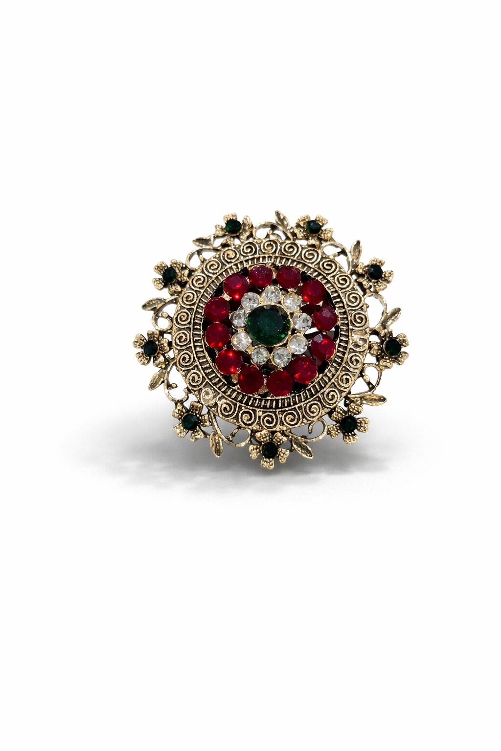 Vintage-inspired round brooch with ruby-red stones, emerald-green center, crystal accents, and intricate antique gold detailing.