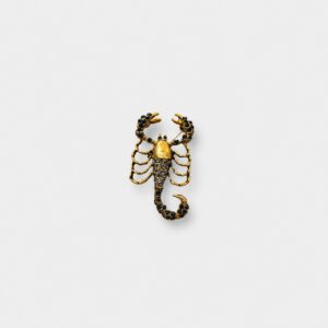 Gold-tone scorpion brooch embellished with black crystals, featuring detailed claws, body, and curved tail in a bold statement design.