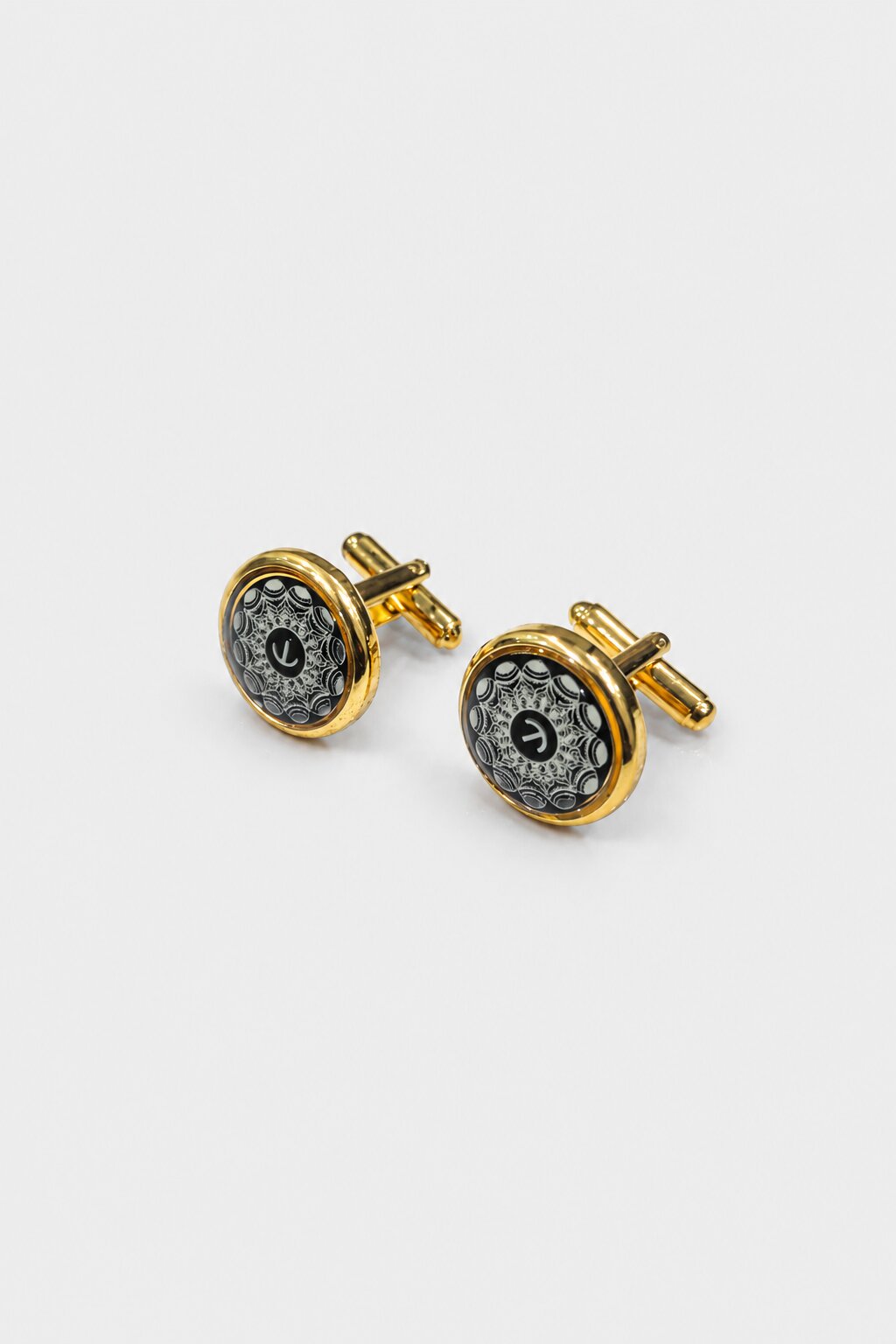Gold round cufflinks with black background and intricate ornamental pattern for men's formal shirts.